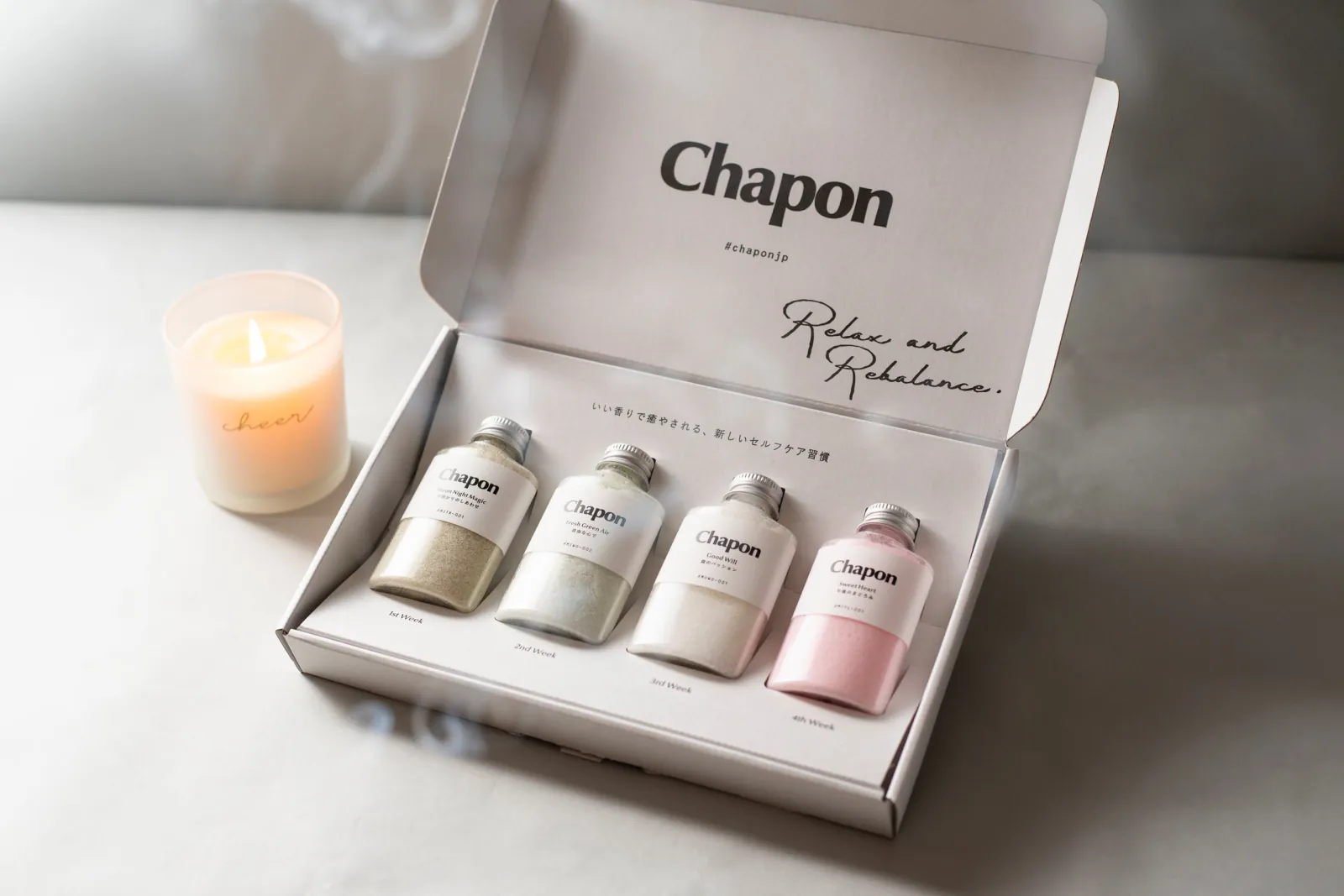灯したキャンドルとともに開けたChaponギフトボックスと入浴剤ボトル4本